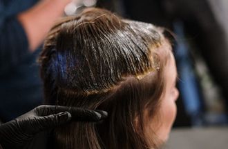 peluquera aplicando un producto en el cabellos de una chica